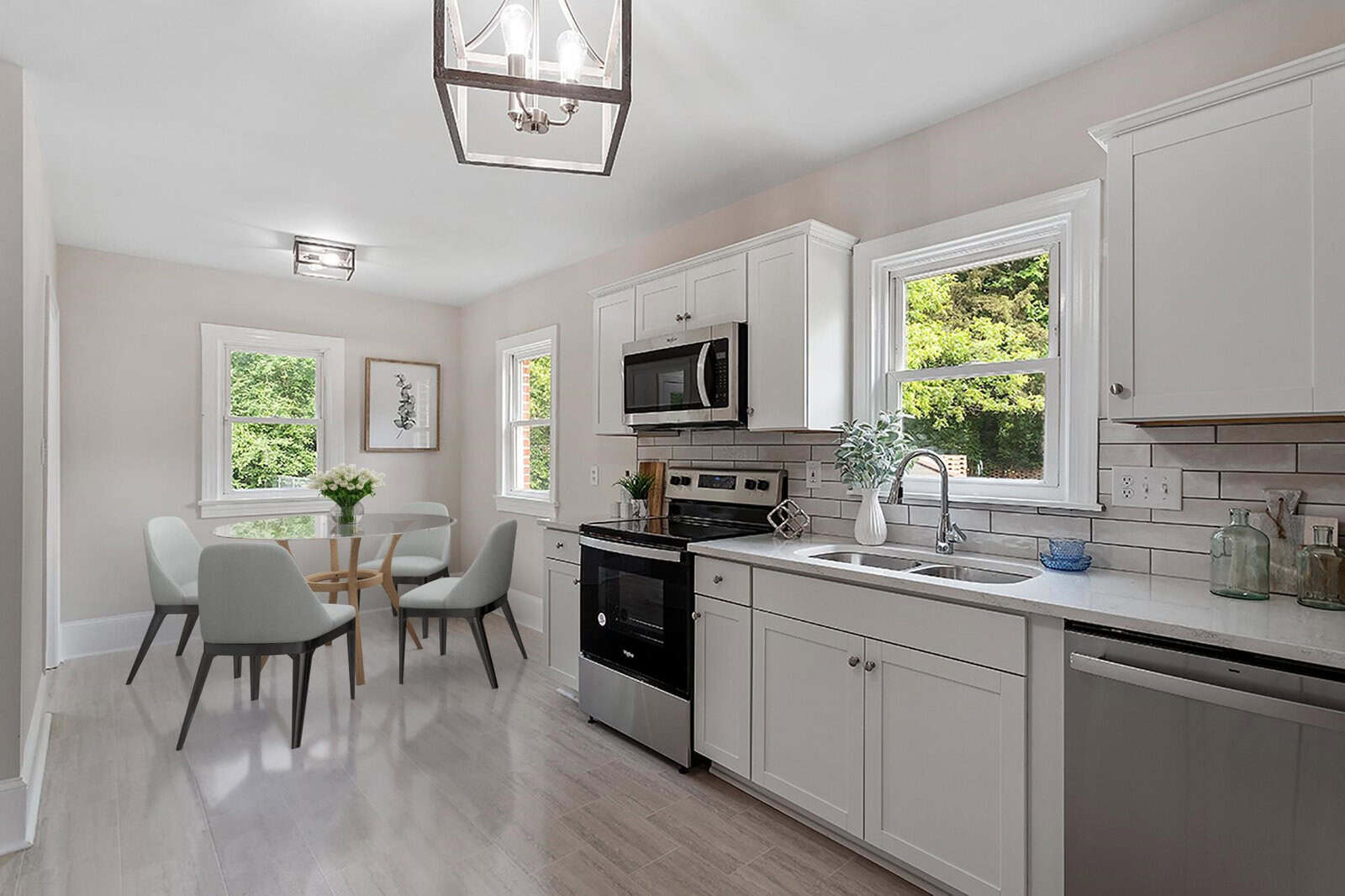 A modern kitchen interior at 146 Lynnhaven Avenue, Henderson NC, with white cabinetry, stainless steel appliances, a dining area with a table set for four, and large windows providing natural light