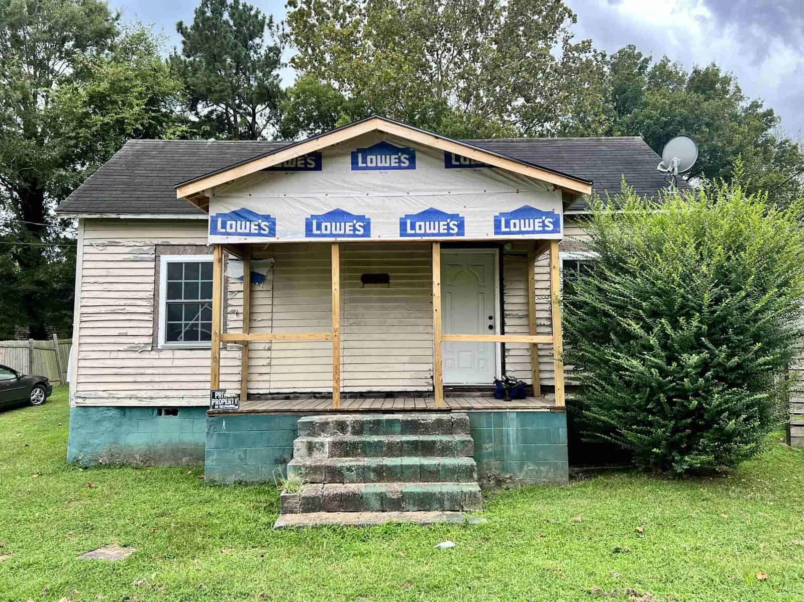 A small house in Henderson, NC, undergoing renovations with a temporary protective covering branded with the Lowe's Home Improvement store logo.