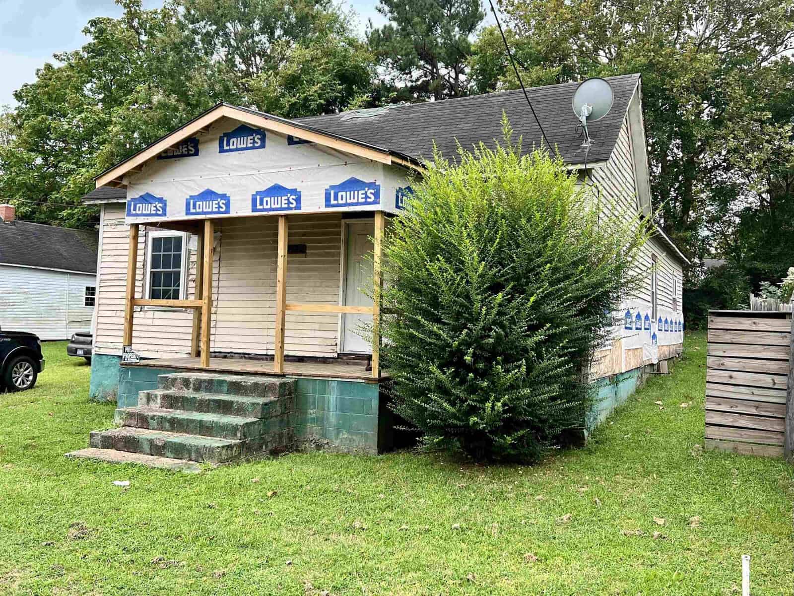 A small house undergoing renovations with visible insulation and lowe's home improvement store branding on the materials.