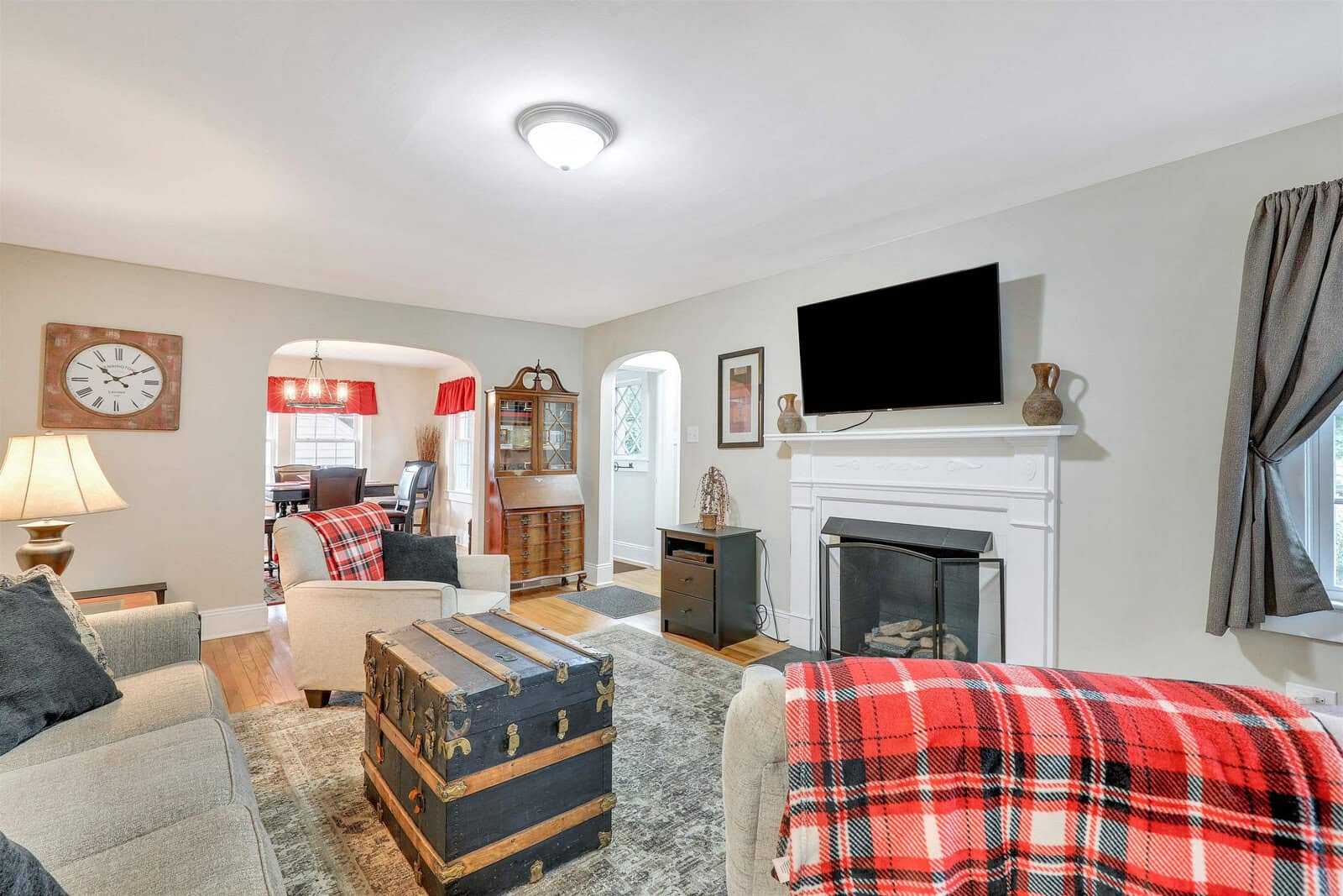 A cozy living room with a fireplace, a mounted television, and furniture adorned with plaid blankets.