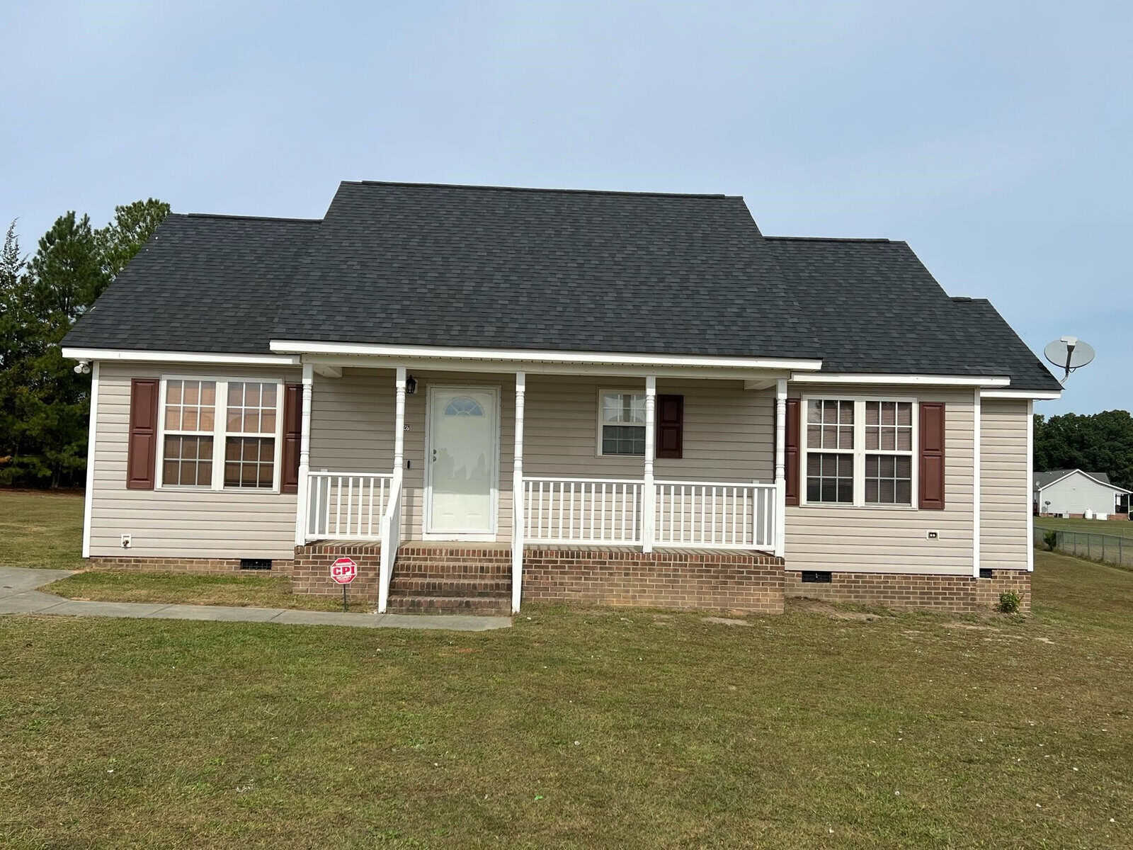 A single-story house with a symmetrical facade, located at 126 Wheat Lane, Henderson NC, featuring a central front door with sidelights, flanked by double windows, a front porch with white