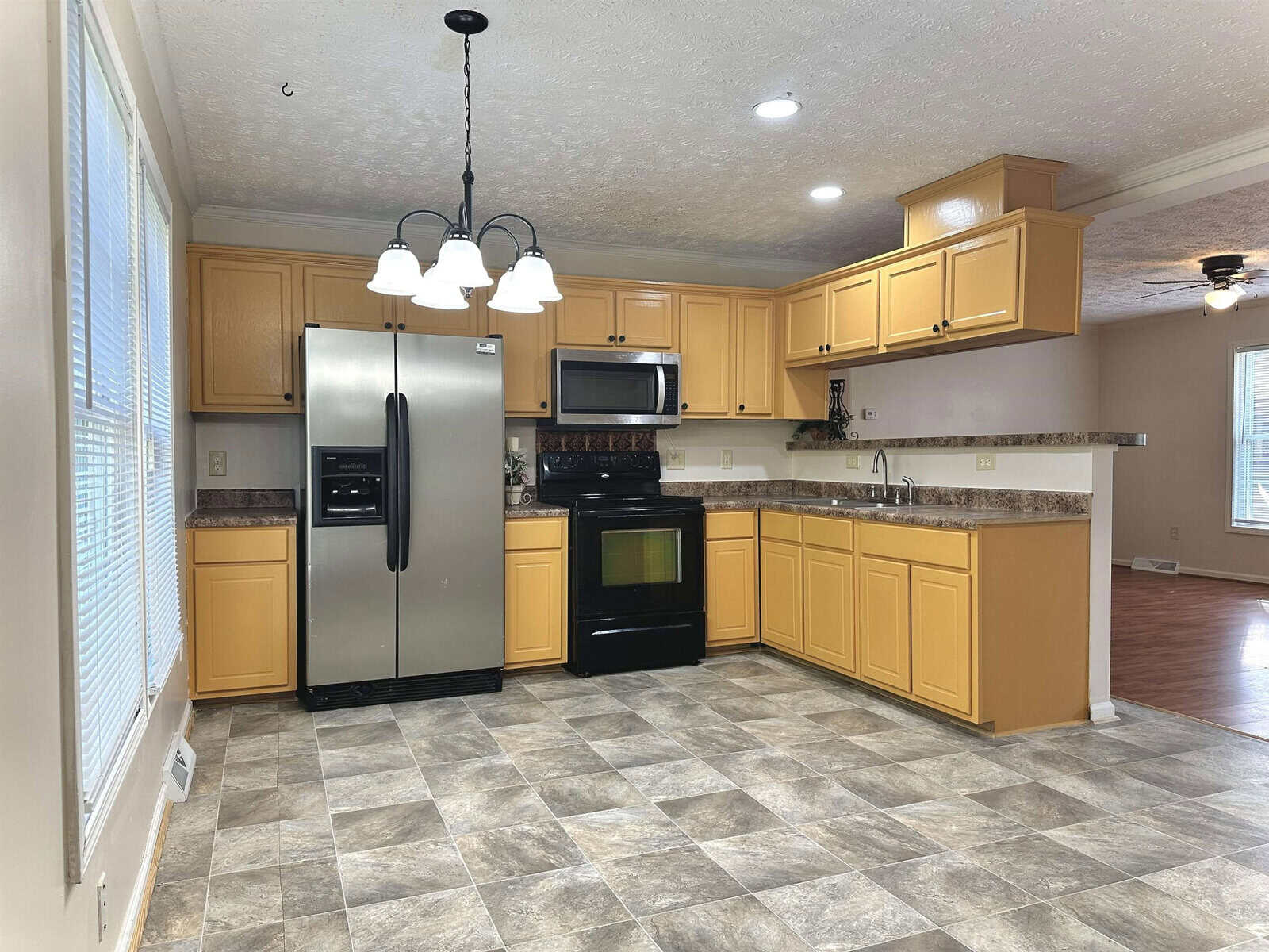 A well-lit, modern kitchen with wooden cabinets, granite countertops, and stainless steel appliances.