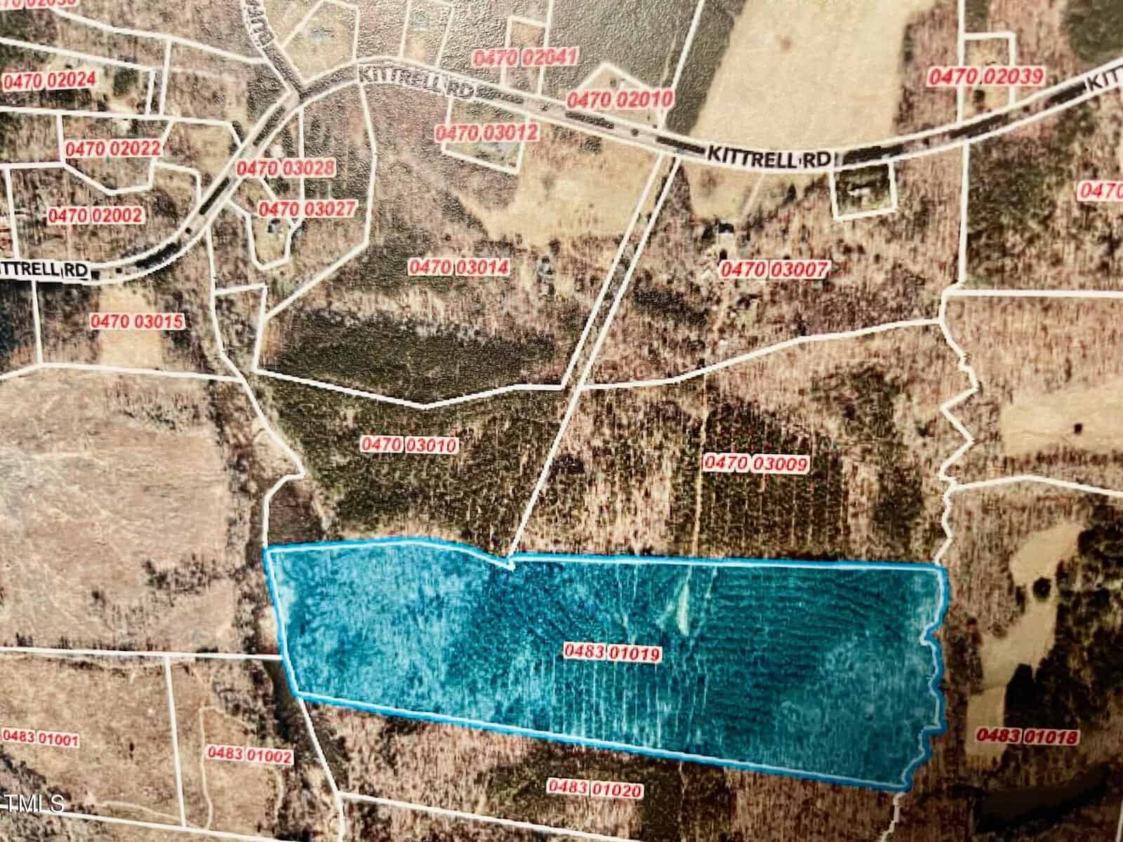 An aerial map showing Kittrell Road with various plots of land labeled with red parcel numbers. One large plot near the bottom is highlighted in blue and labeled as parcel 0483.01019. Surrounding plots also have visible parcel numbers.