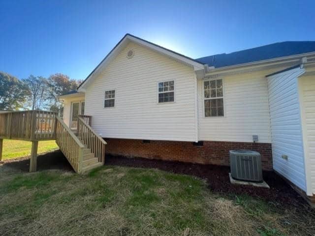 A single-story house with vinyl siding and a set of wooden stairs on a sunny day.