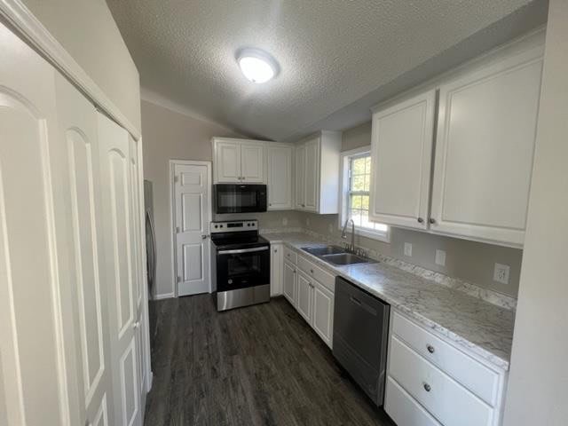 A modern kitchen interior with white cabinetry, stainless steel appliances, and light-colored countertops, complemented by gray wood-like flooring.