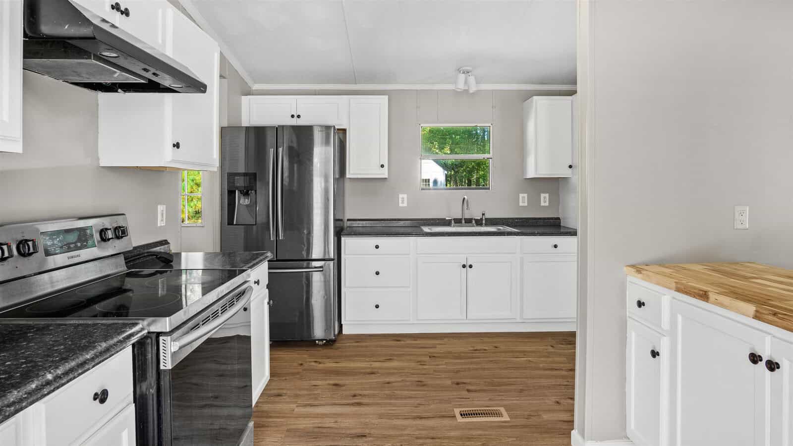 Modern kitchen interior with white cabinetry, stainless steel appliances, and dark countertops.