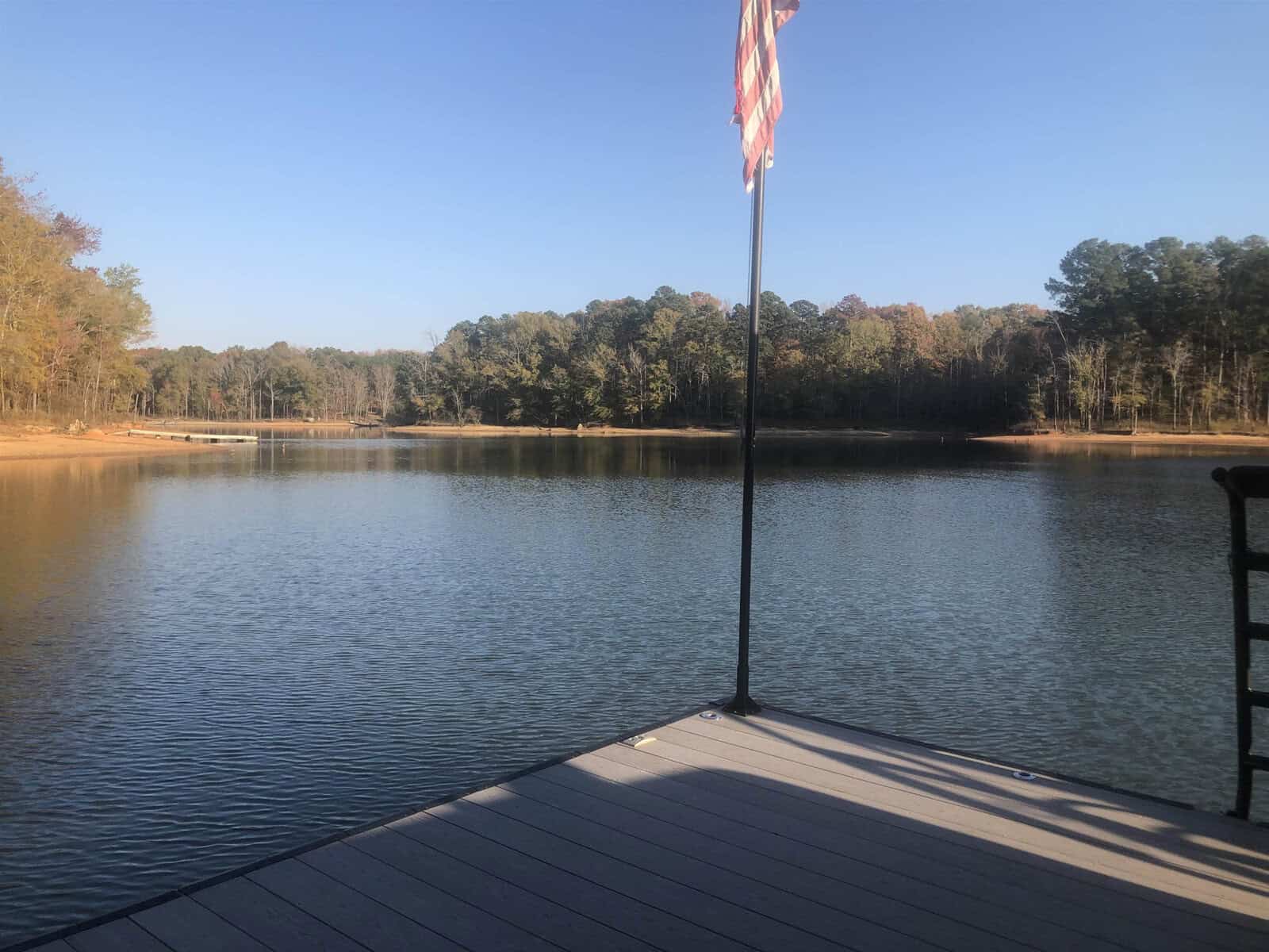 A serene lake view from a wooden dock with an american flag displayed on the right.